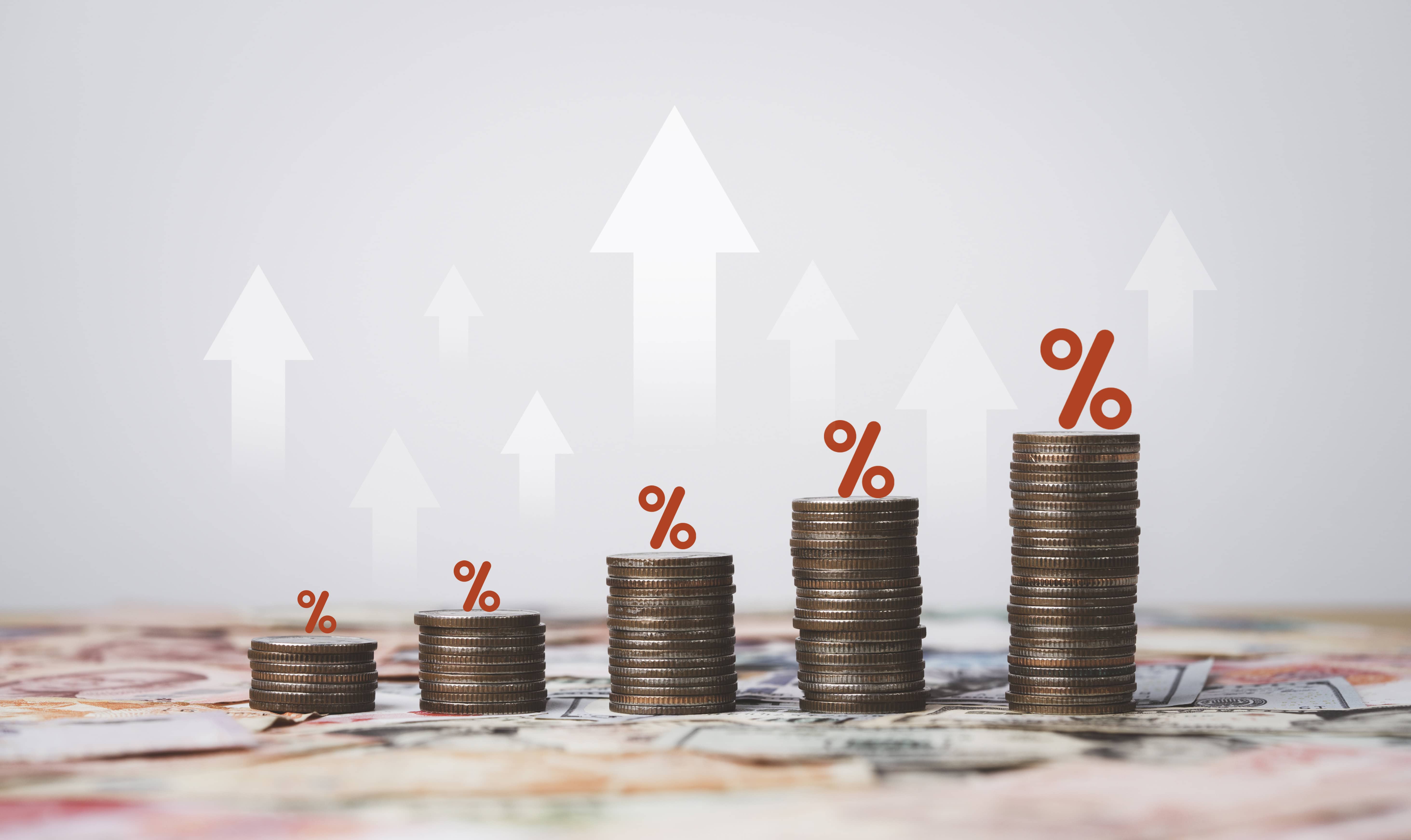 Coins stacking with white up arrow and percentage on international banknote for increasing Financial interest rate and inflation concept.